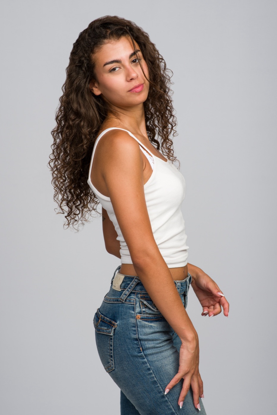 Vitoria de espaldas girando la cabeza, top blanco y vaquero